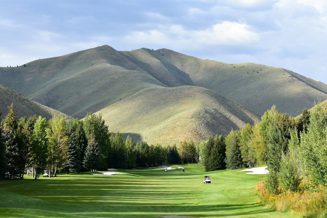 Golfer teeing off on a mountain golf course with Wasatch peaks in the background